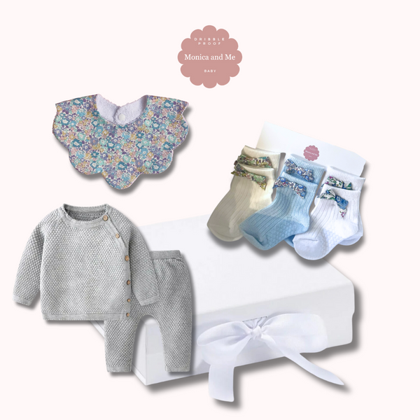 Baby gift box that includes baby socks with Liberty London bows, Scalloped baby bib in Michelle blue print, grey knitted set of top and leggings.