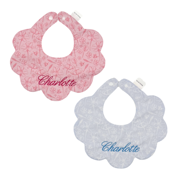 Set of pink and blue Tulip print Liberty scalloped baby bibs, shown with personalised monogramming