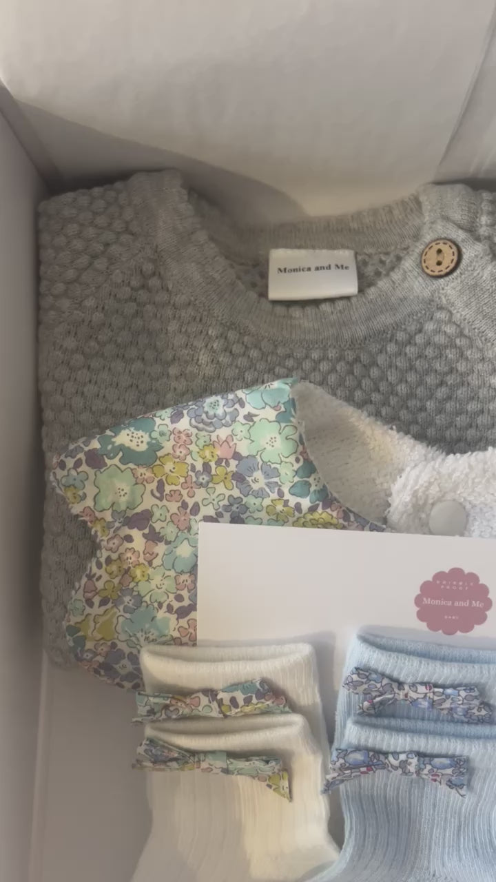 Baby gift box that includes baby socks with Liberty London bows, Scalloped baby bib in Michelle blue print, grey knitted set of top and leggings.